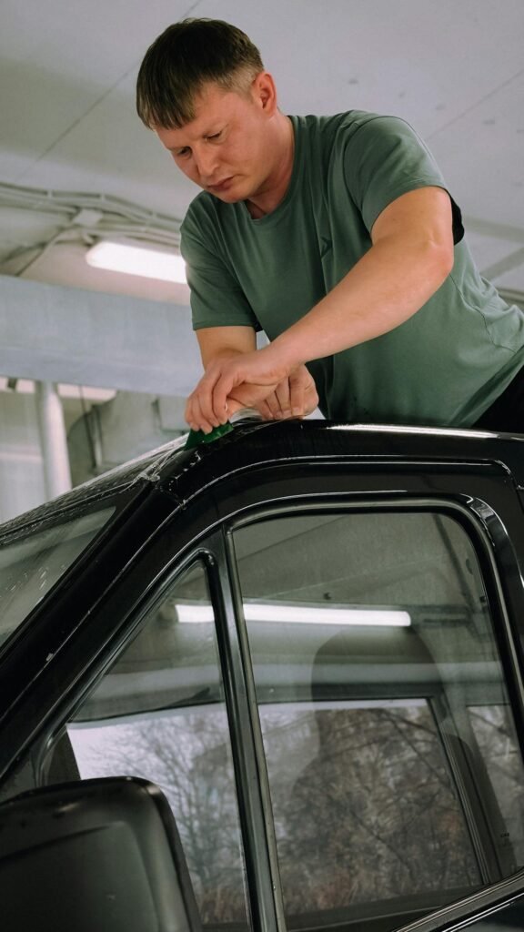 Man applying window tint film to a car with a squeegee