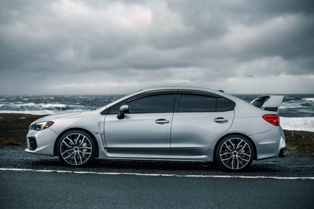 Silver sedan with tinted windows parked by a stormy coastline