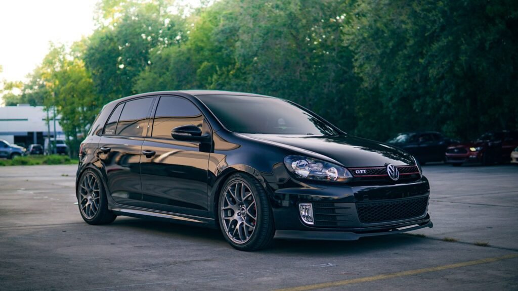 Black hatchback with tinted side and rear windows in a car park